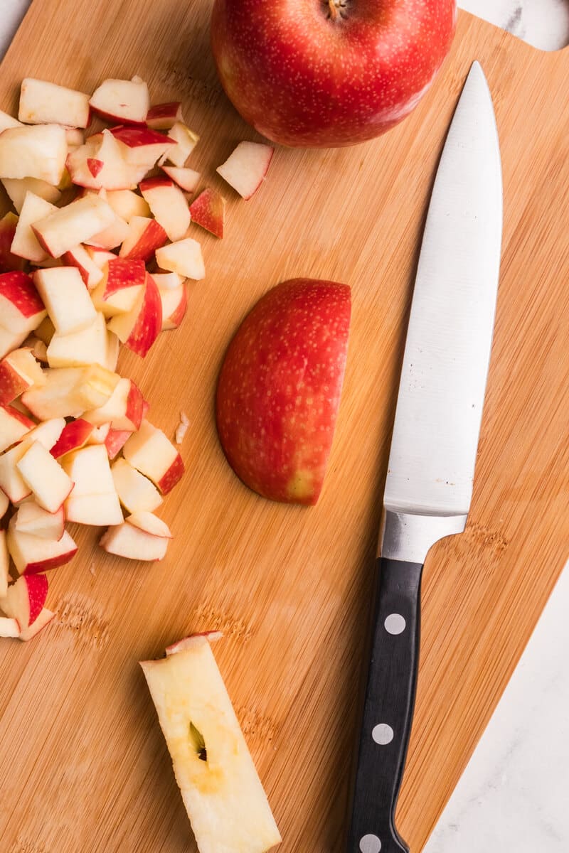 sliced apple and apple chunks on a cutting board with a knife.