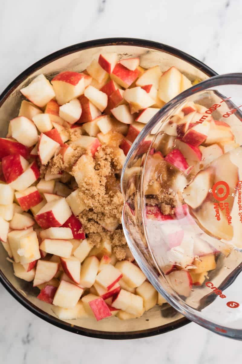 pouring water over a pot of chopped apples and brown sugar.