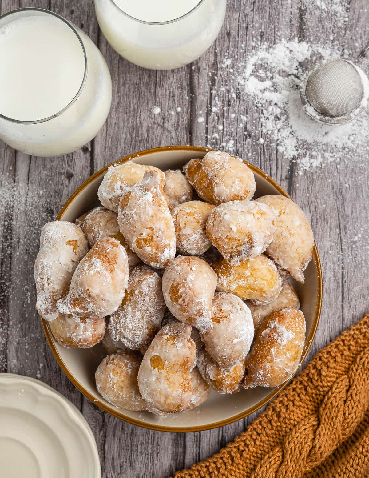 a bowl of powdered sugar dusted gluten free hush puppies.