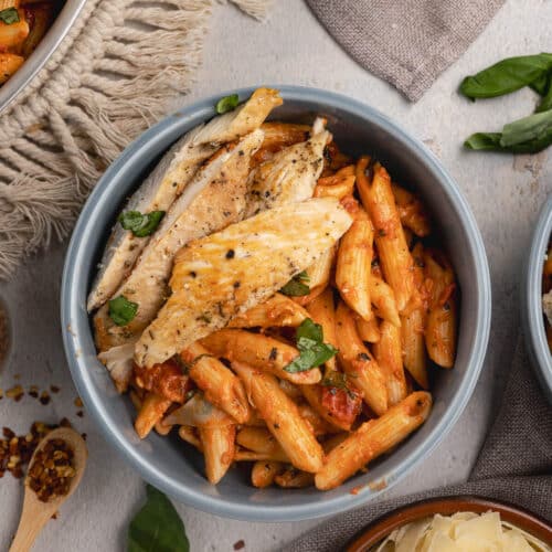 a bowl of vodka pasta with sliced chicken on top