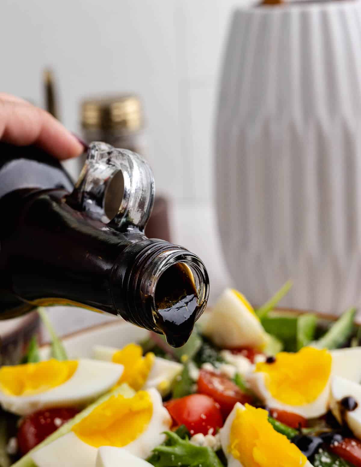 about to pour fig vinaigrette onto a salad.