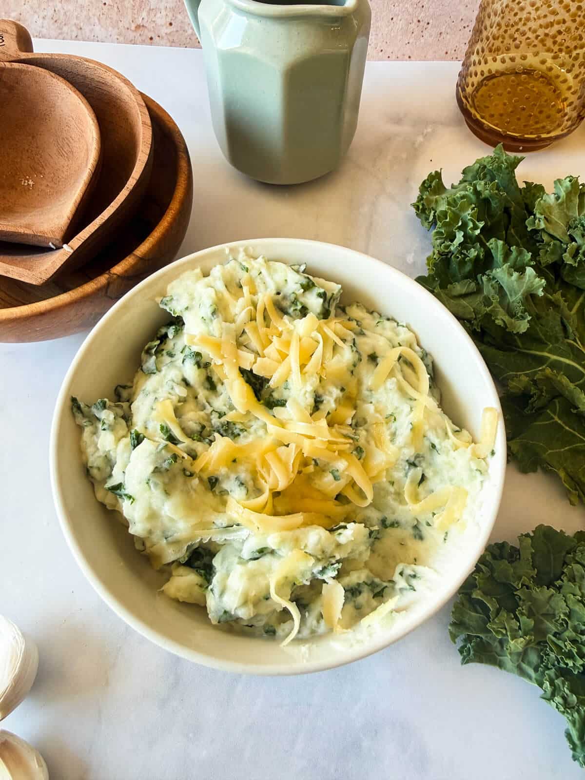a bowl of gouda and kale mashed potatoes with shredded gouda on top.