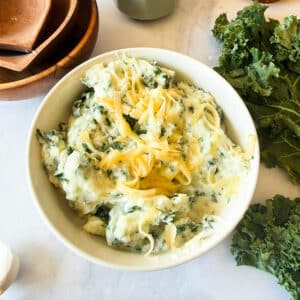 a bowl of gouda and kale mashed potatoes with shredded gouda on top