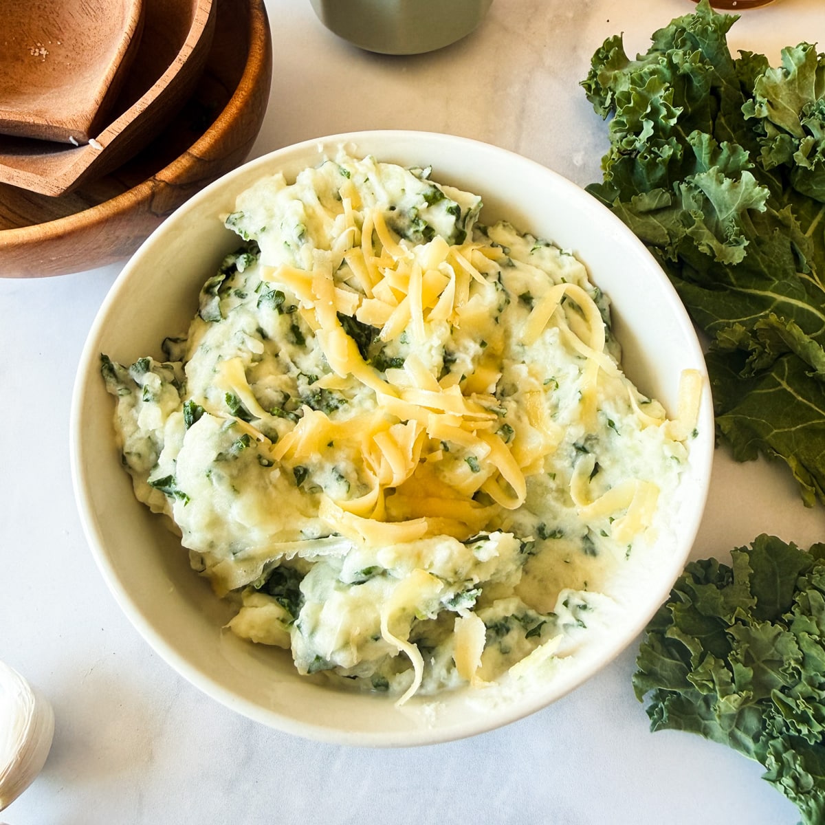 a bowl of gouda and kale mashed potatoes with shredded gouda on top