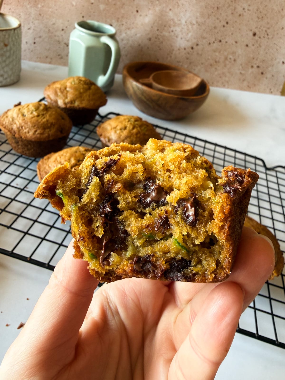 hand holding half a zucchini muffin