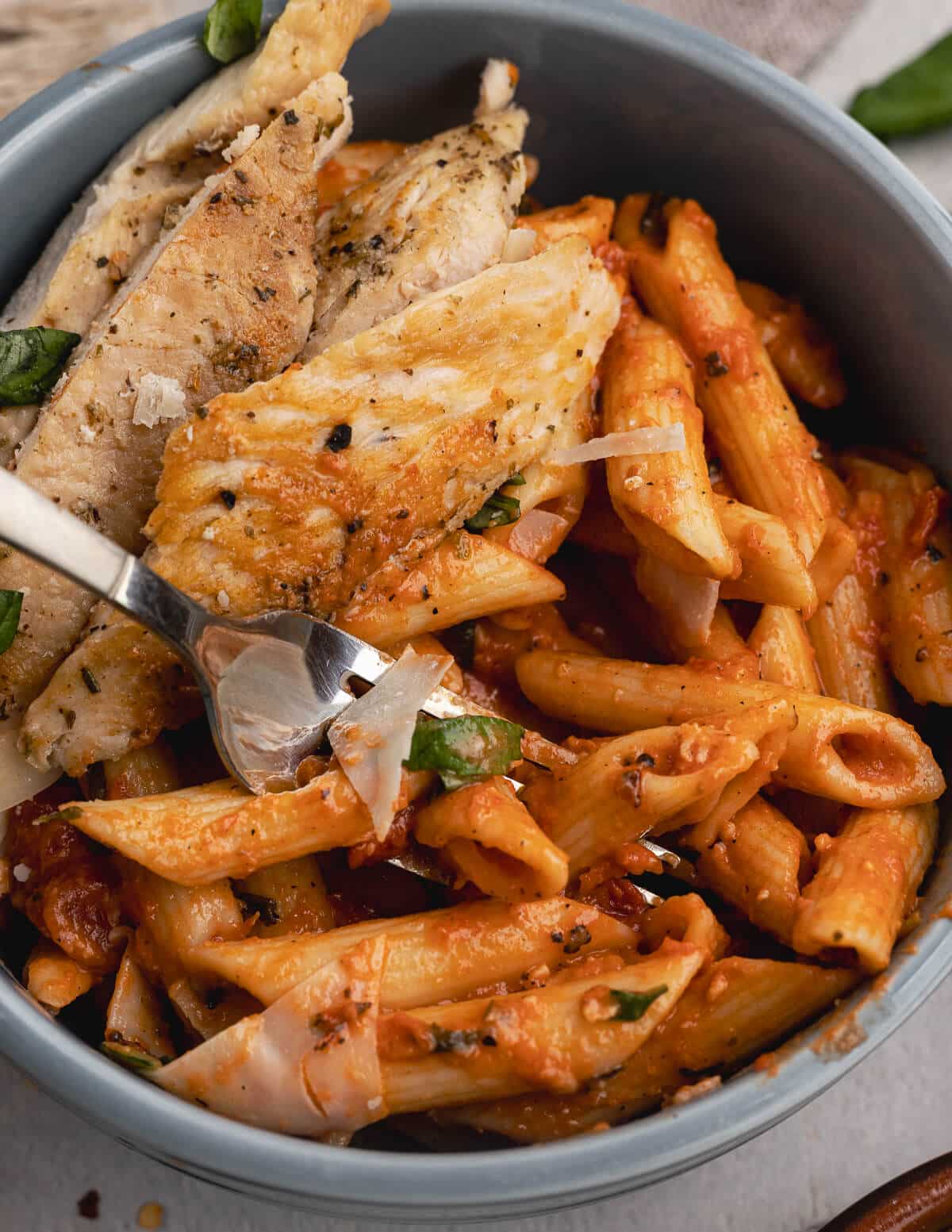 a bowl of vodka pasta with chicken on top.