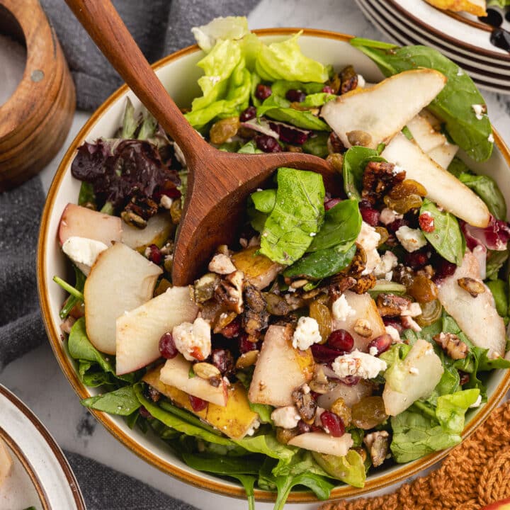 salad with pears, pomegranate seeds, and golden raisins on top.