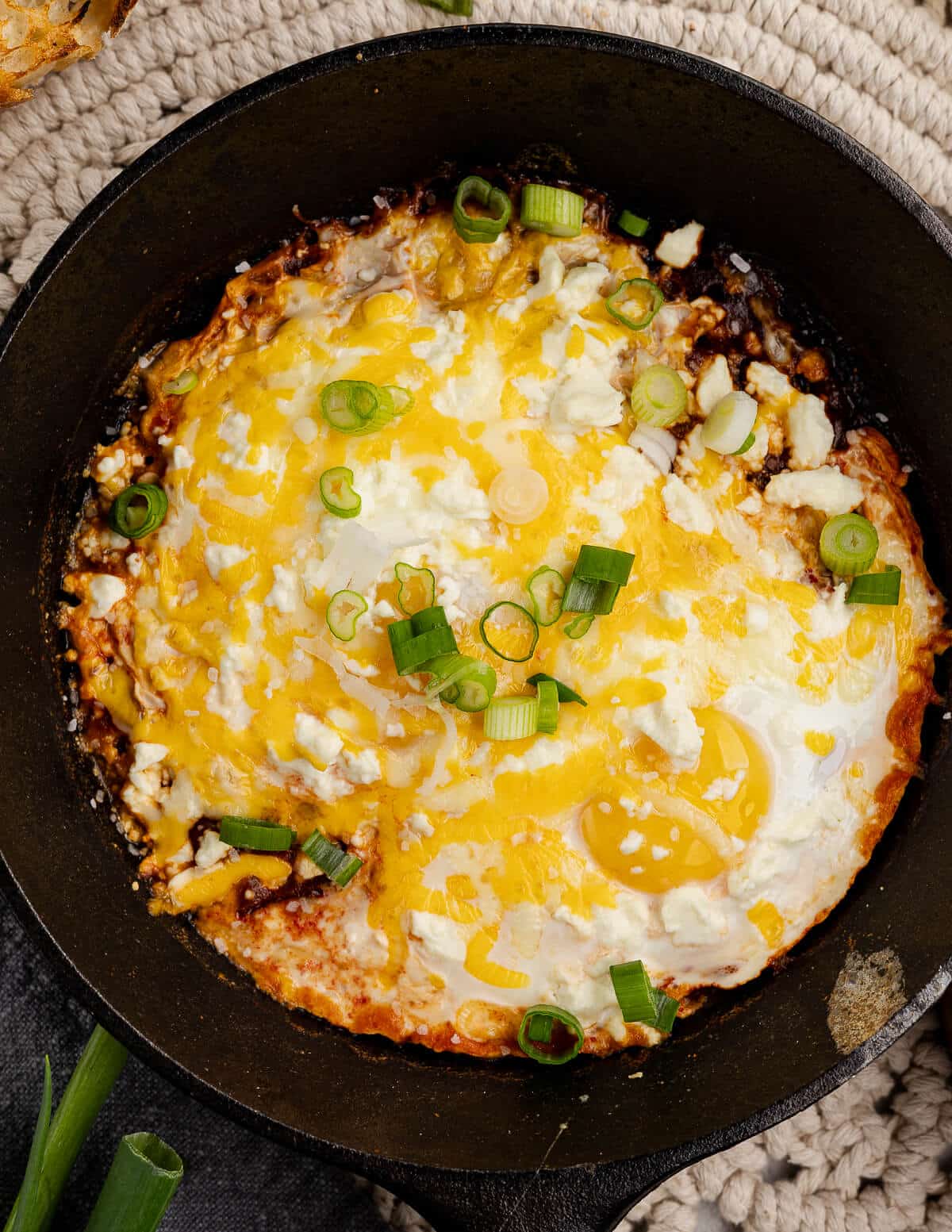 a skillet with salsa, eggs, and melted cheese on top.