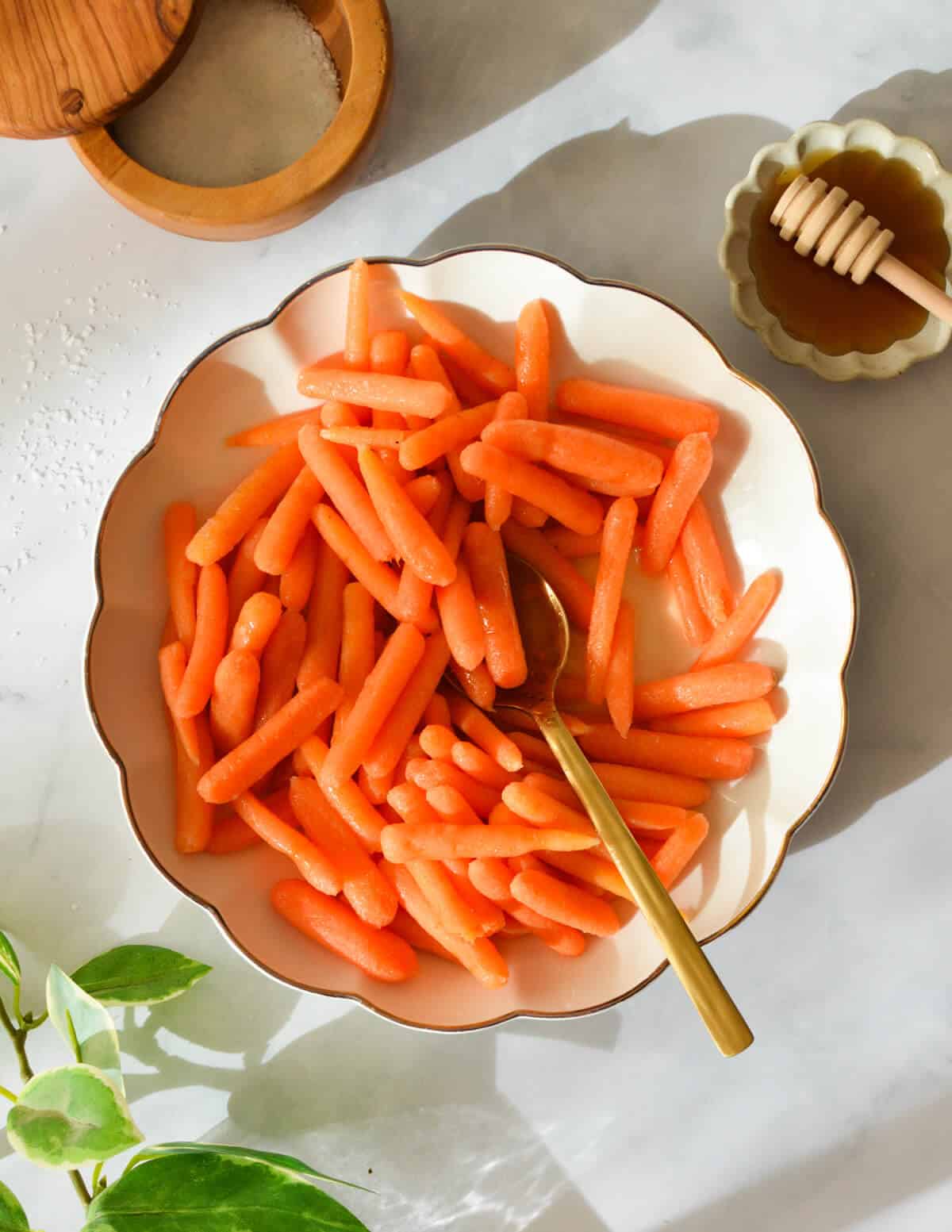 a bowl of steamed carrots with a gold spoon in it.