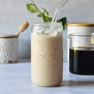homemade frosted coffee in a glass cup with a glass straw