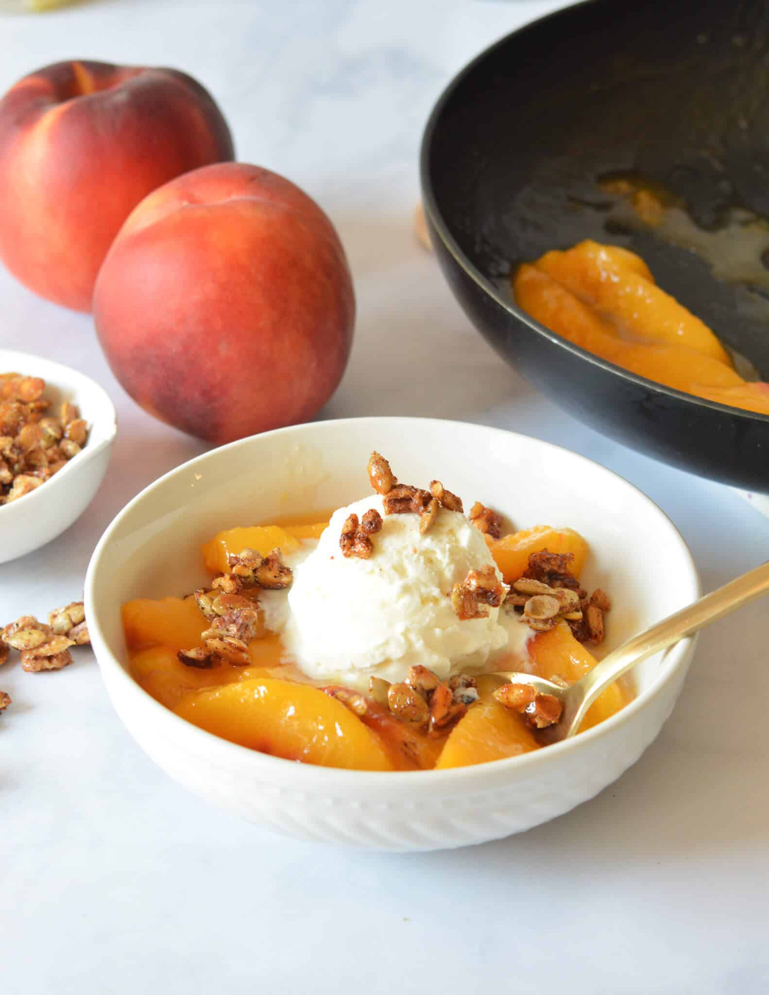 a bowl of candied peaches with ice cream and candied nuts on top.