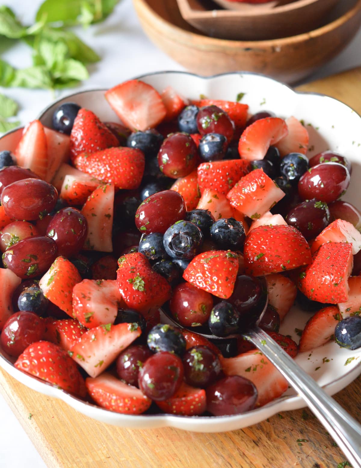 a bowl of strawberries, blueberries, and grapes with mint