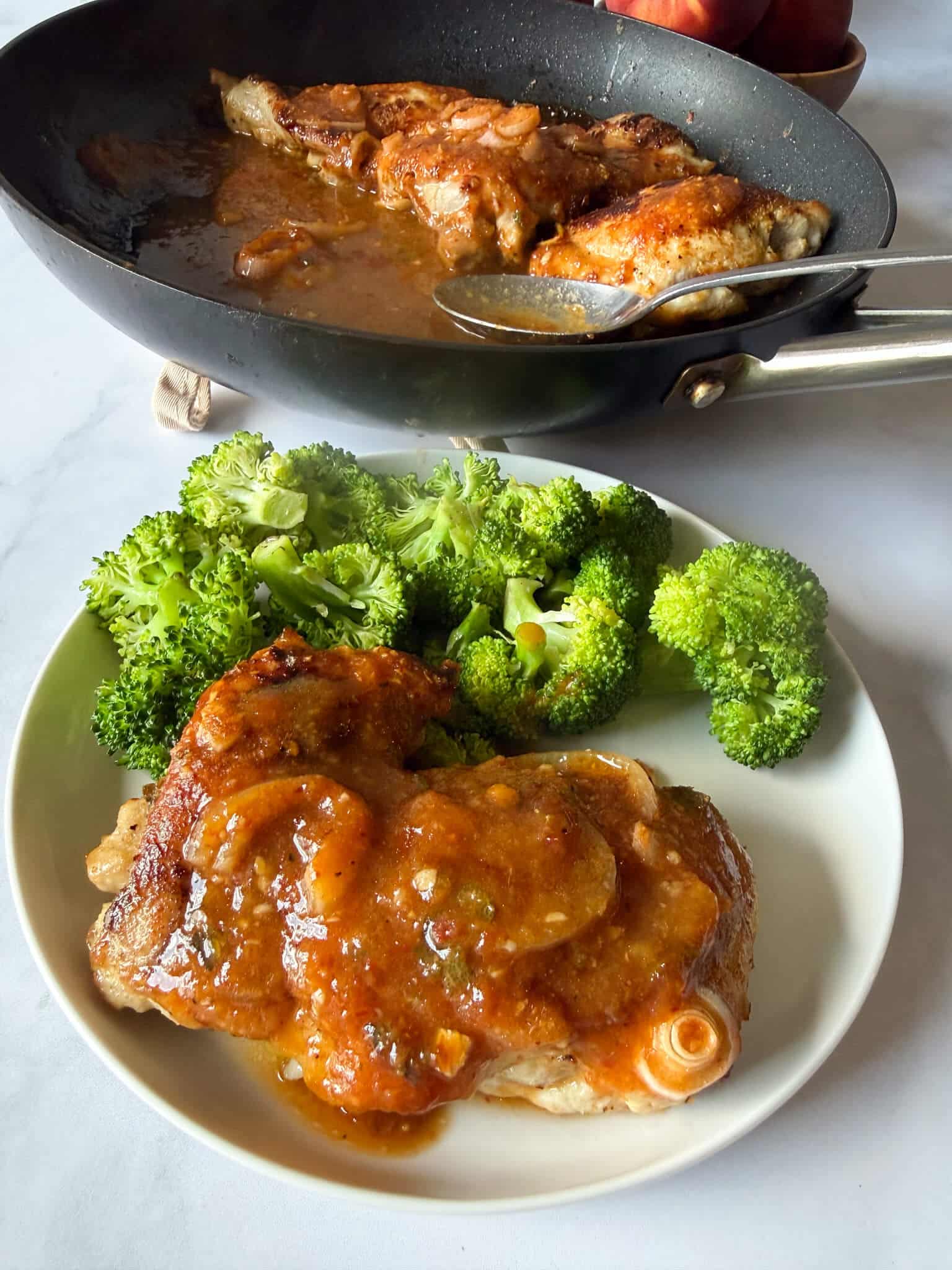 chipotle peach chicken thighs on a plate with steamed broccoli