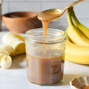 spoonful of banana syrup drizzling into cup