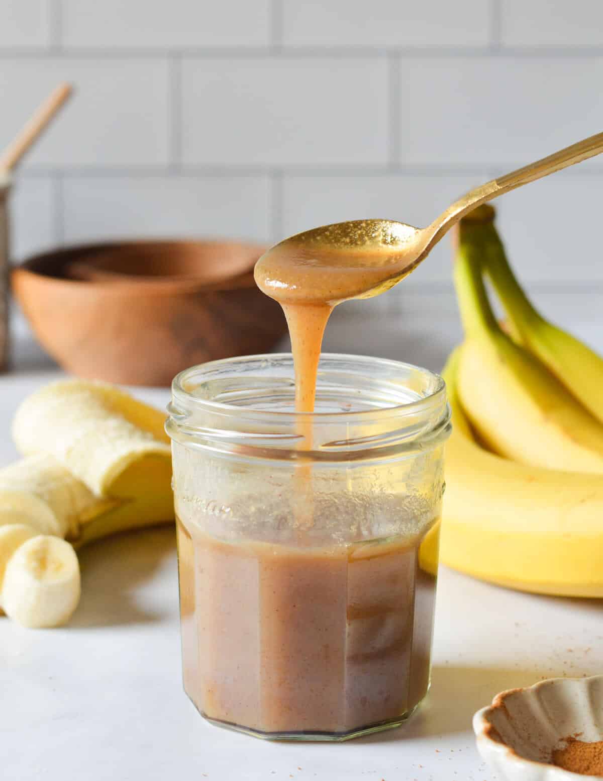 pouring banana syrup into a glass with a spoon.